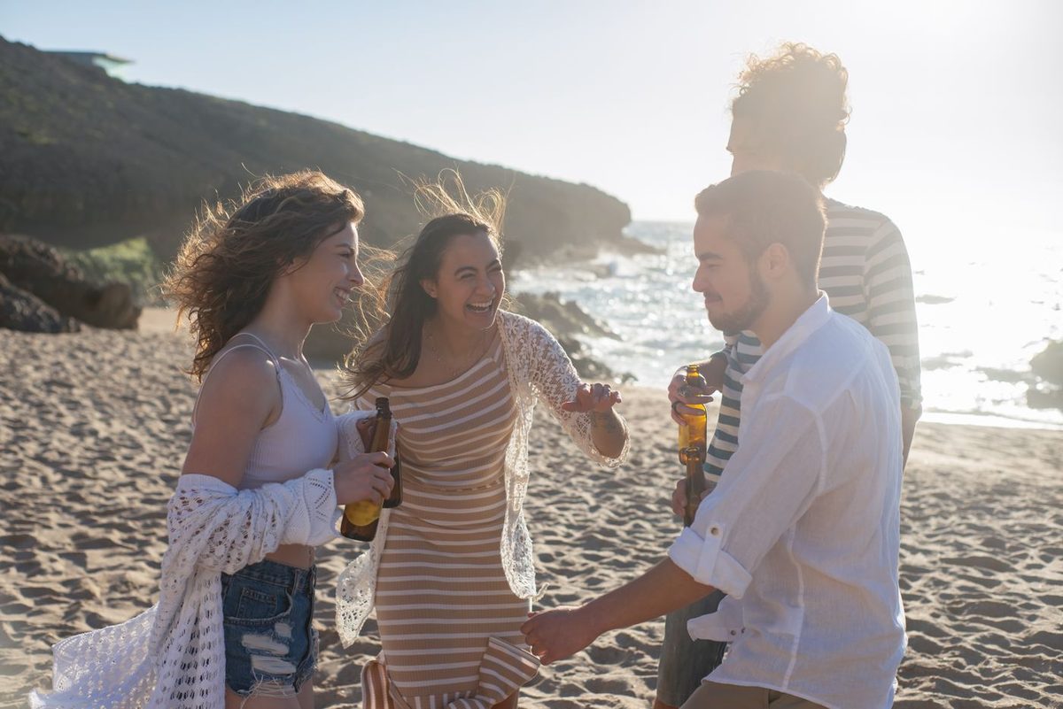 Grupo de amigos riéndose juntos en la playa durante una salida grupal